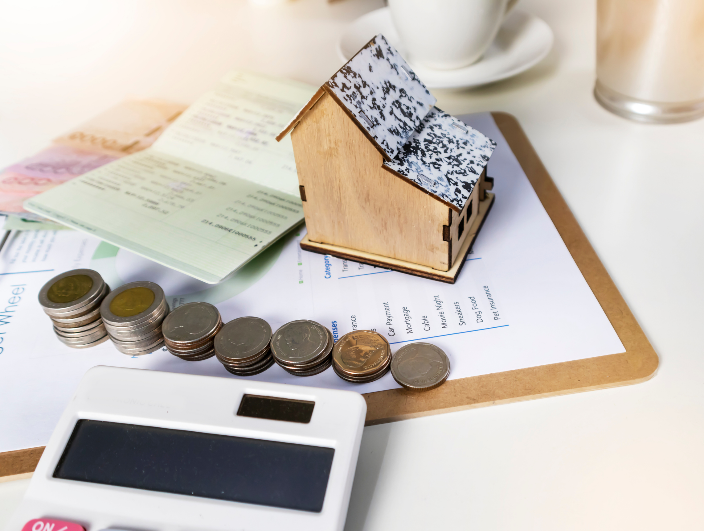 A model house next to coins and paperwork depicting home loan.